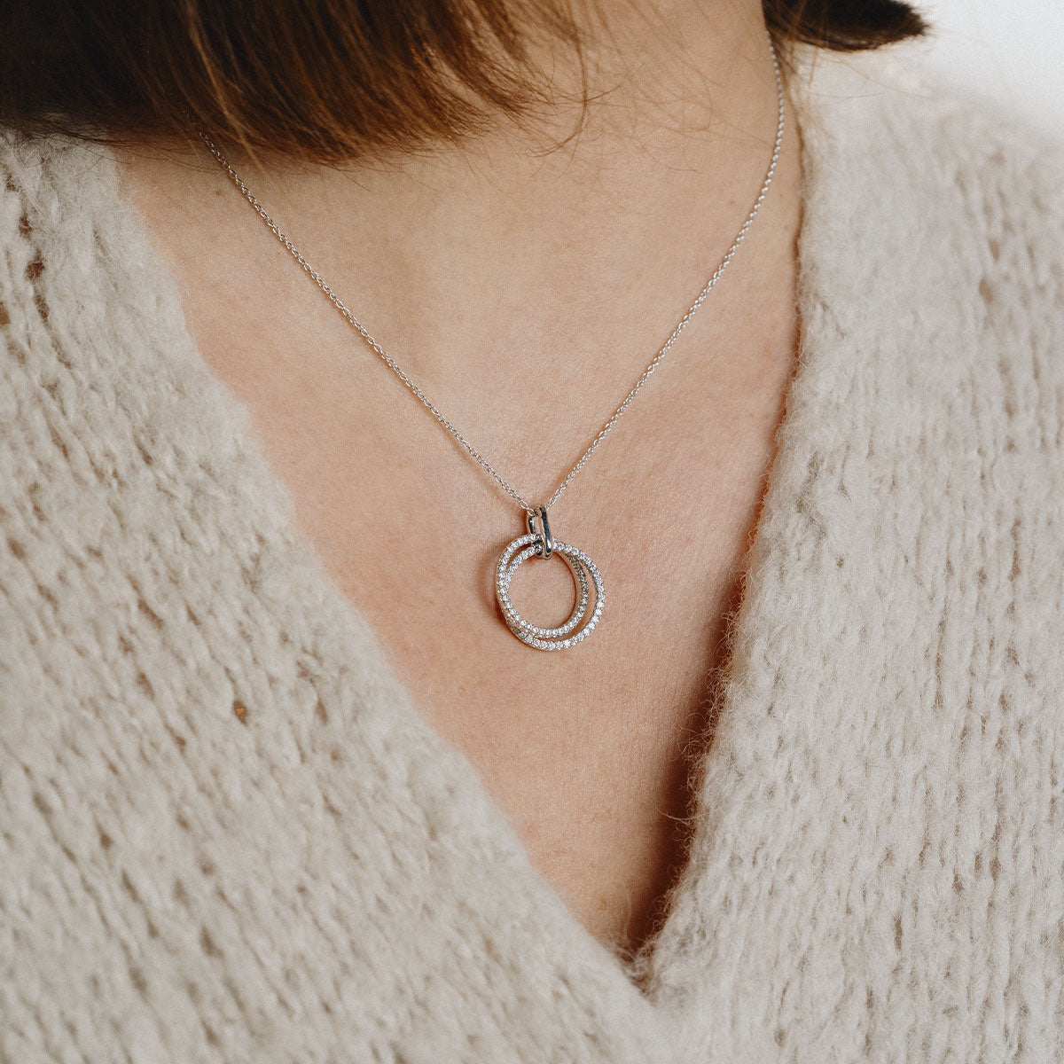 Round silver necklace with white zirconia stones and two entwined circles